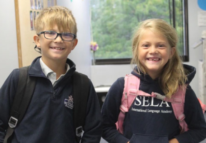 Smiling girl and boy, students with jumper and logo of SELA school